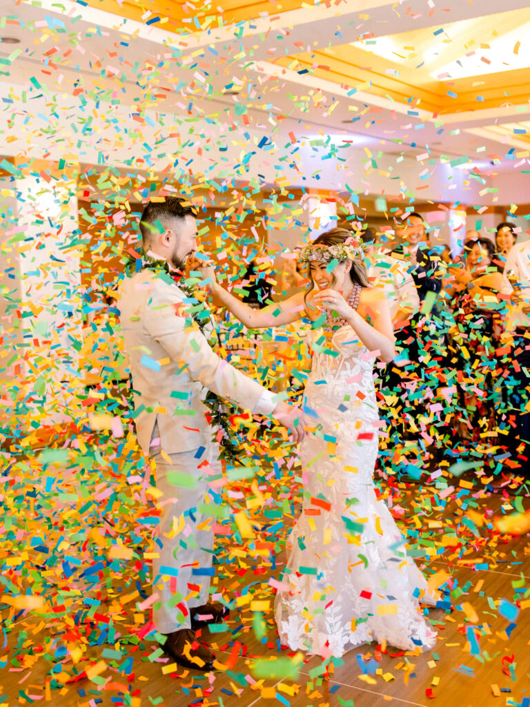 A joyful wedding scene with a couple dancing amid vibrant confetti.