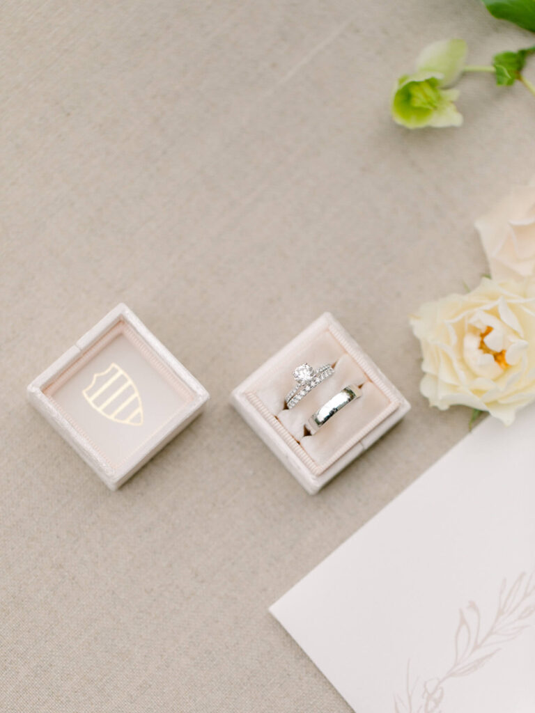 An elegant engagement ring and wedding band set in a beige velvet box on a linen surface.