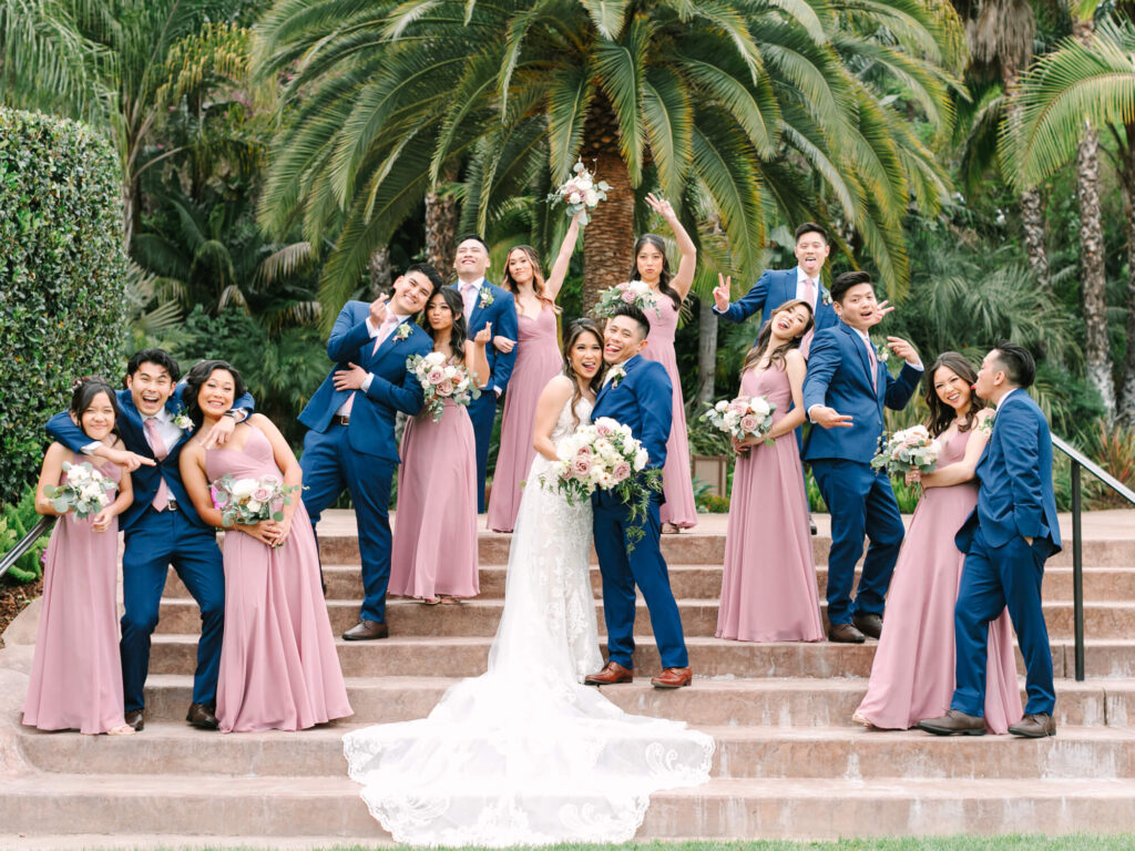 Wedding party cheering on garden steps with lush greenery at Grand Tradition Estate and Gardens.