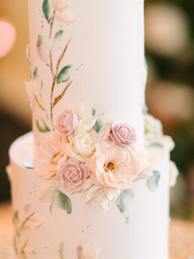 Two-tier white cake with pink and white floral decorations.