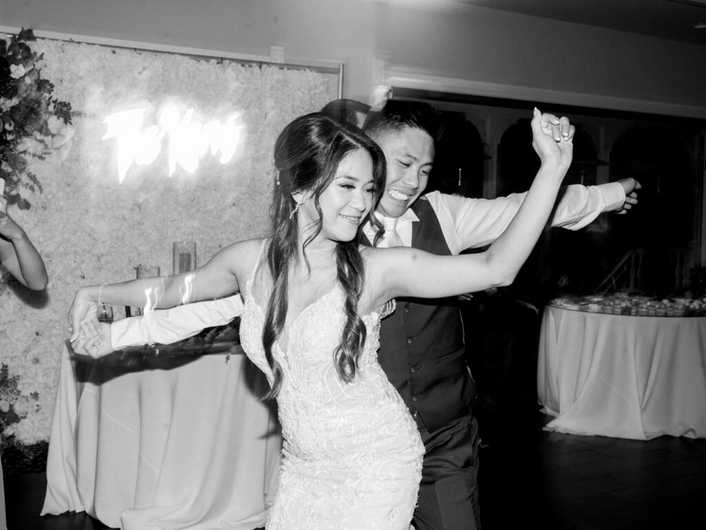 A joyful couple dances closely, smiling and dressed in formal attire.
